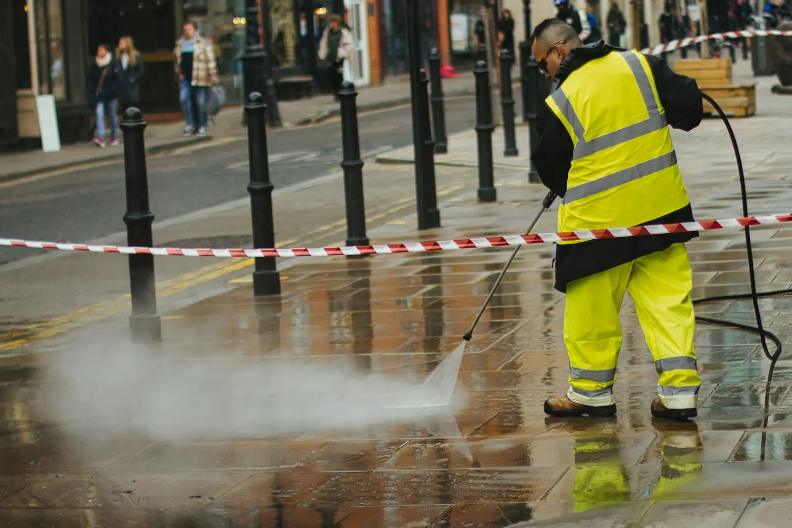 Worker pressure washing wet paving